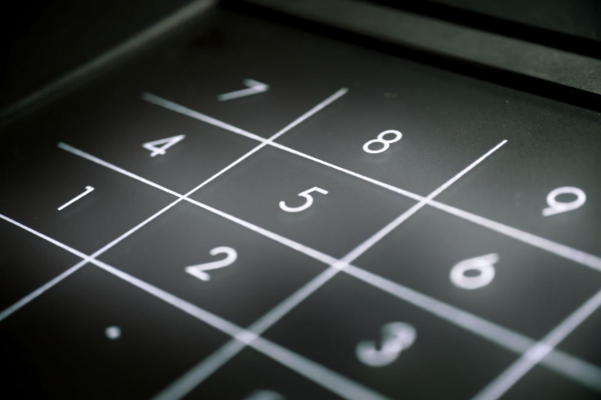 Gros plan sur le clavier numérique rétroéclairé d'un boîtier de commande industriel, en contre-plongée.